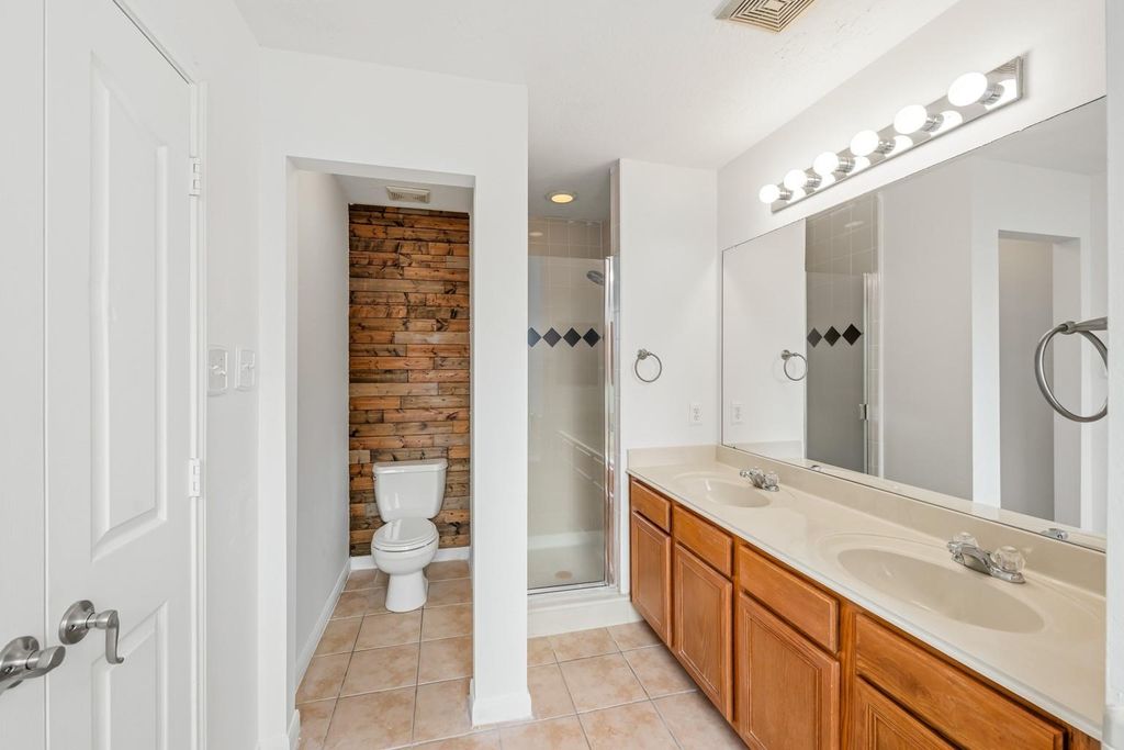 4908 Summer Rain Dr, Conroe, TX 77303 Bathroom with a dual vanity and wood accent wall